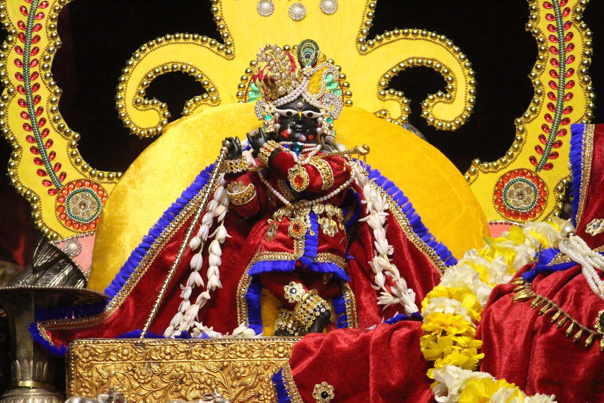 लाल पोशाक में बैंगनी किनारे के साथ श्री राधारमण जी।