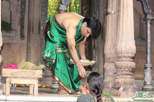 Sewayat of Shri Radharaman Temple is giving prashad to a devotee.