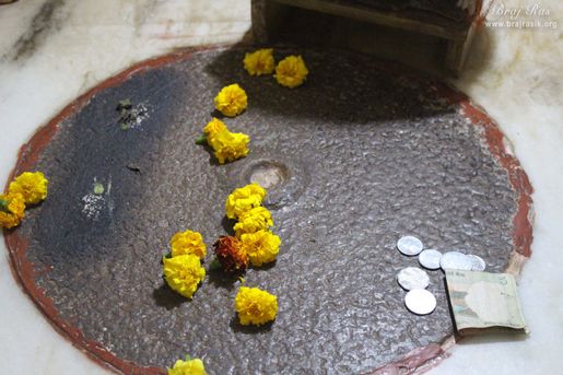 Charan darshan of Shri Krishna on a grindstone at Jhadu Mandal, Vrindavan