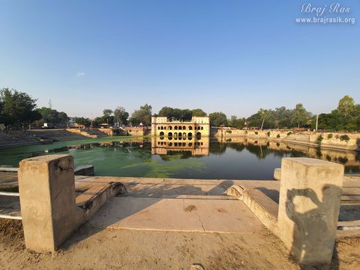 A Front full view of Sri Vrishbhanu Kund (Jal Mahal), Barsana surrounded by trees all around.