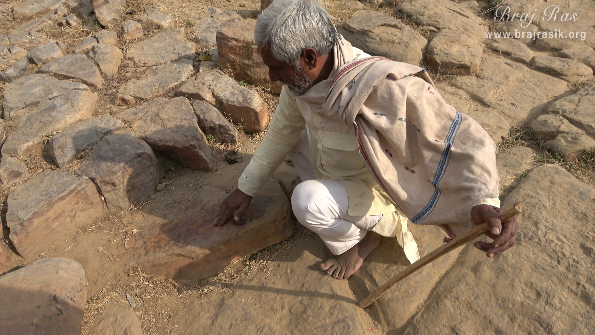 A Brajwasi is rubbing his fingers on Sinduri Shila at Govardhan to get Sindur (vermillion).