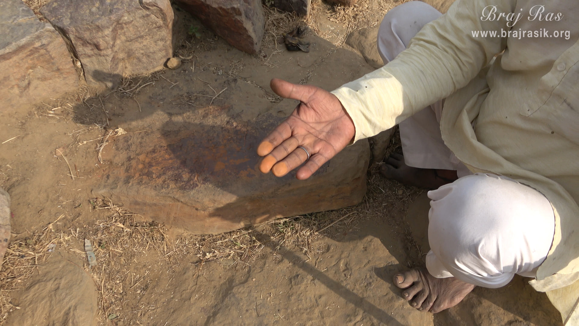 A Brajwasi is showing Sindur (vermillion) by rubbing his fingers on Sinduri Shila at Govardhan.