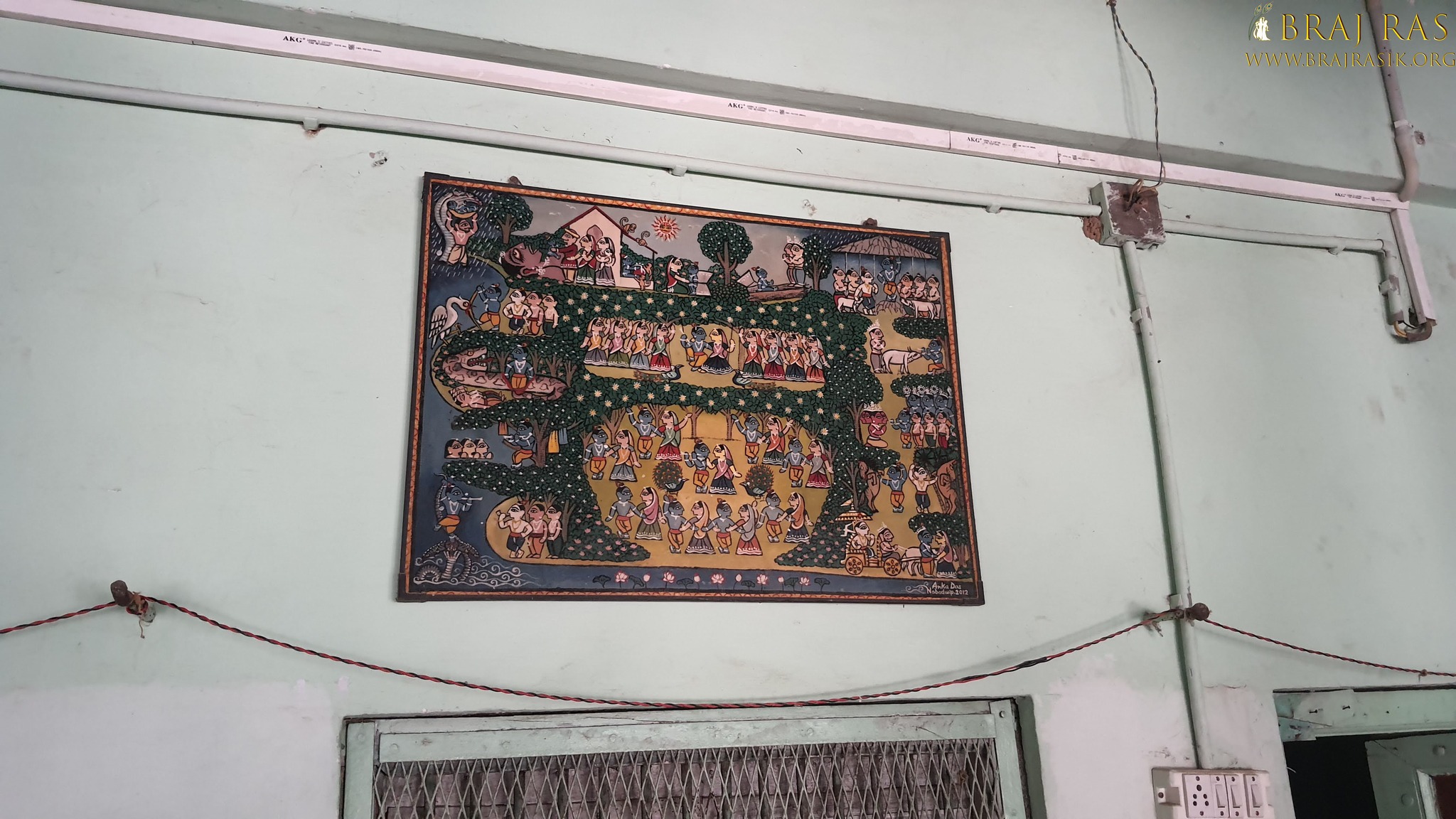 View of a picture depicting various pastimes of Shri Radha Krishn hanging on a wall inside Bhagwat Niwas, Vrindavan.