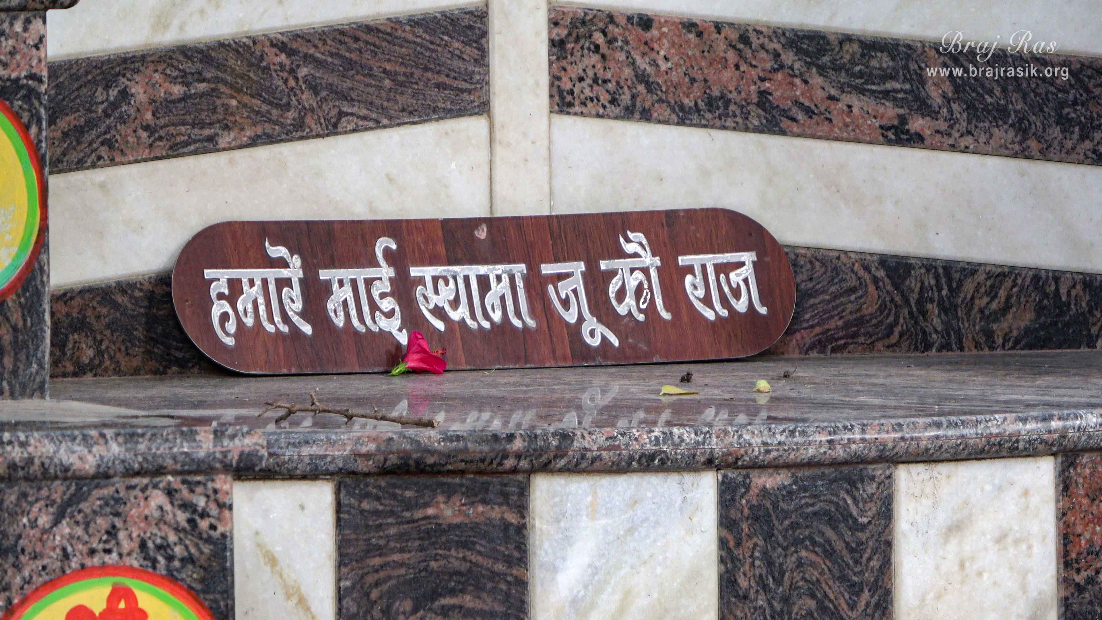 A verse written "Humare Mai Shyama Ju Ko Raaj" on a wooden plate is placed on the Sinhasan of Raas Sthali in Kirti Tapah Sthali inside Khelan Van, Padar Van, Barsana.